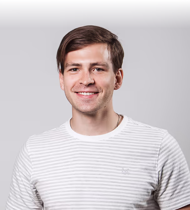 Serhii Storozhev smiling in a striped t-shirt against a grey studio wall