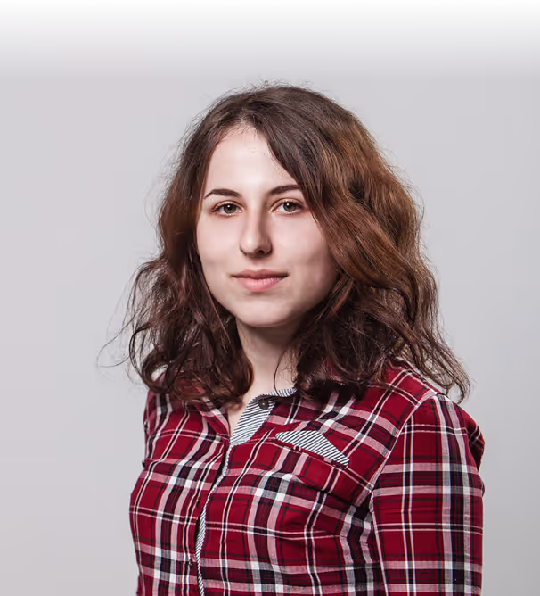 Kateryna Polyshchuk in a red plaid shirt against a grey studio wall