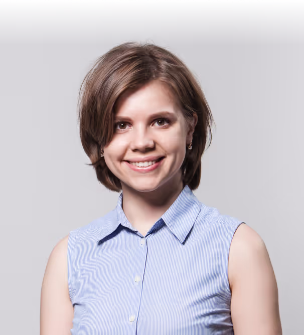 Anastasiia Shyrokykh smiling in a light blue sleeveless shirt against a grey studio wall